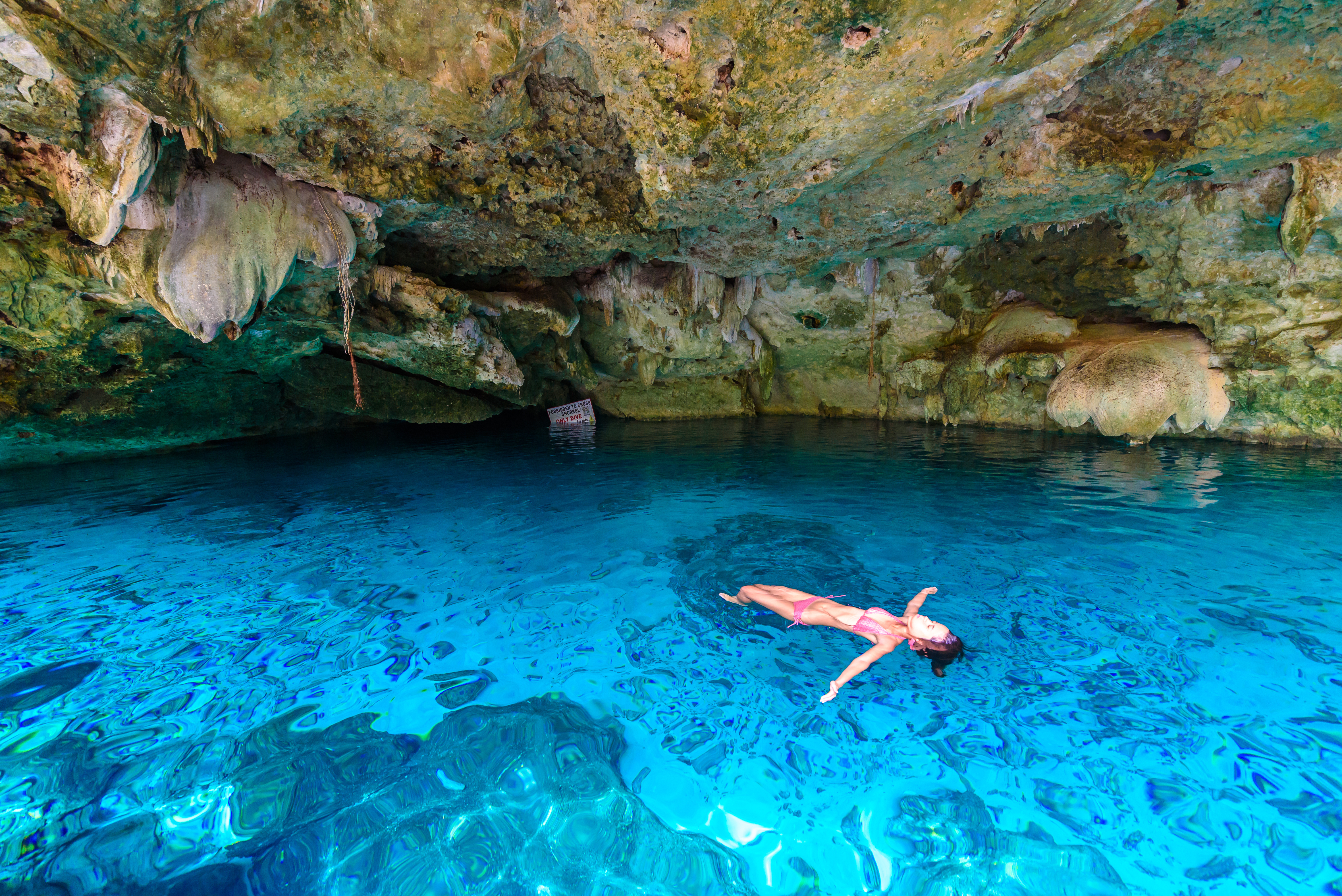 Frau liegt auf dem Wasser in einer Unterwasserh&ouml;hle